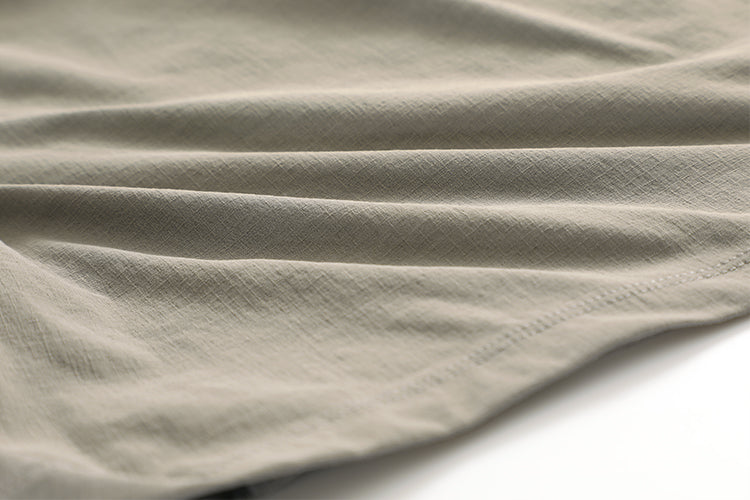 Gros plan d'un t-shirt CRZ Yoga beige, parfait pour les aventures en plein air, sur une surface blanche.